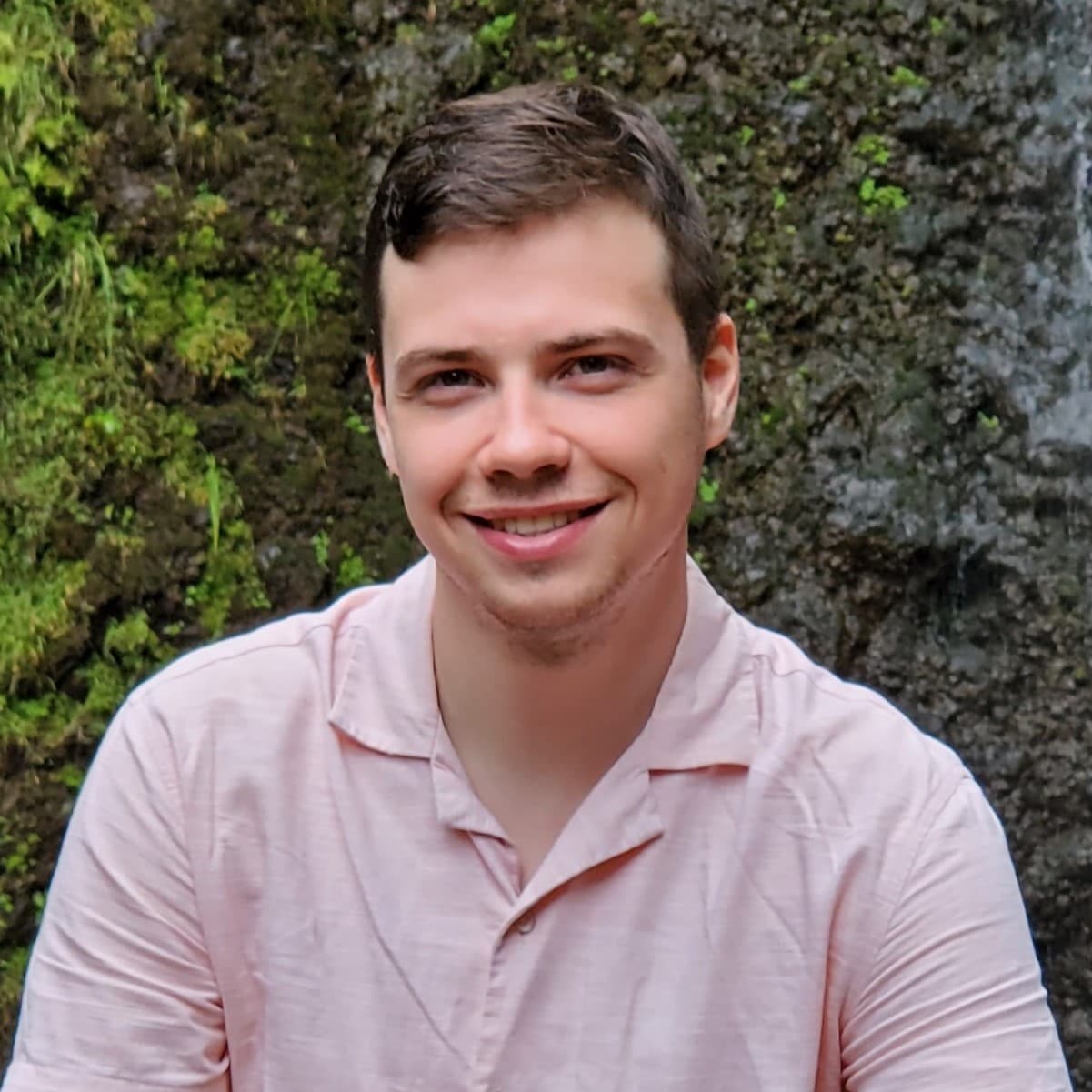 Paul McJannet in pink shirt with waterfall in background